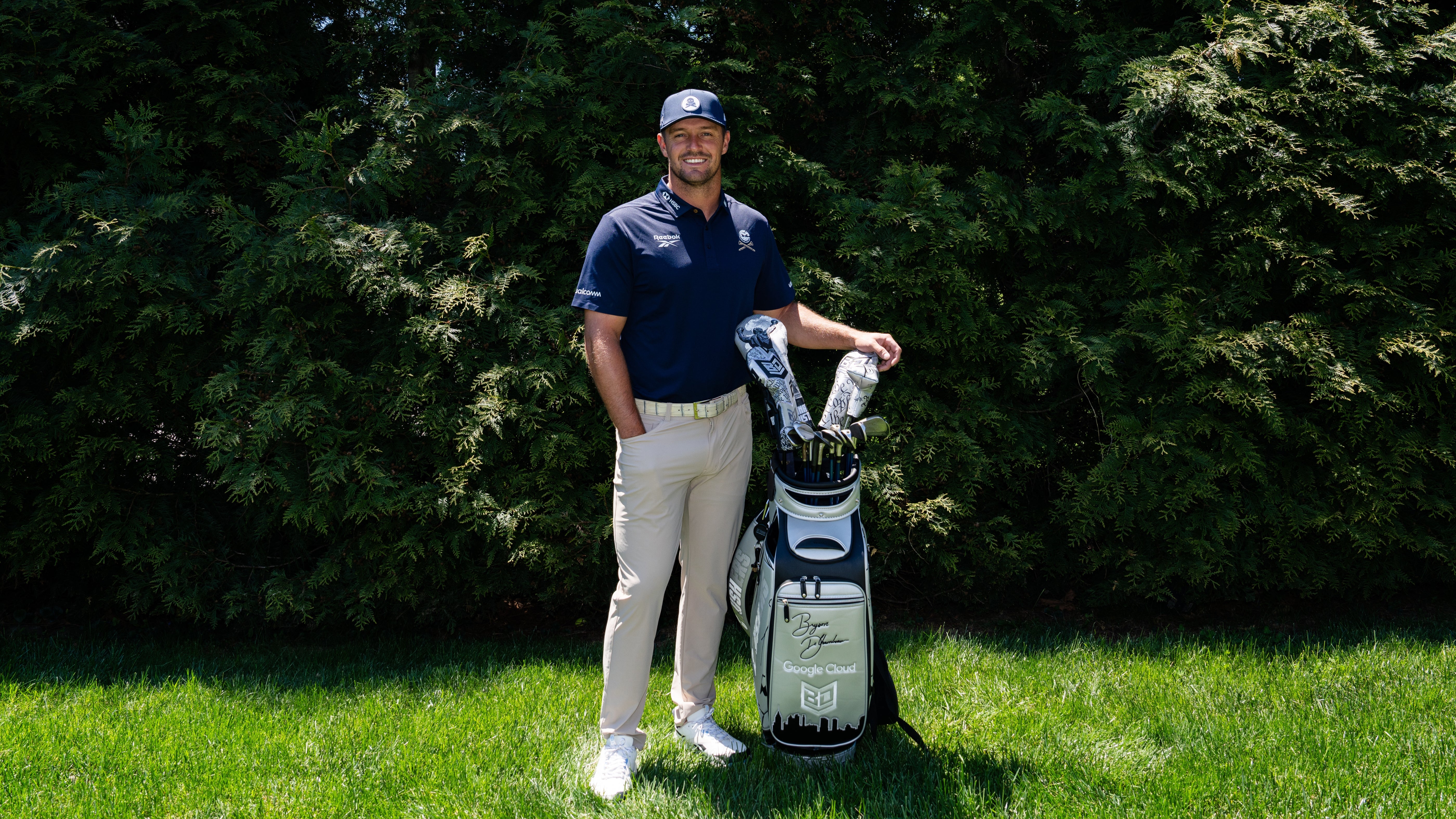 Bryson DeChambeau standing with his limited edition SWAG Golf headcover collection featuring Philly themed designs.