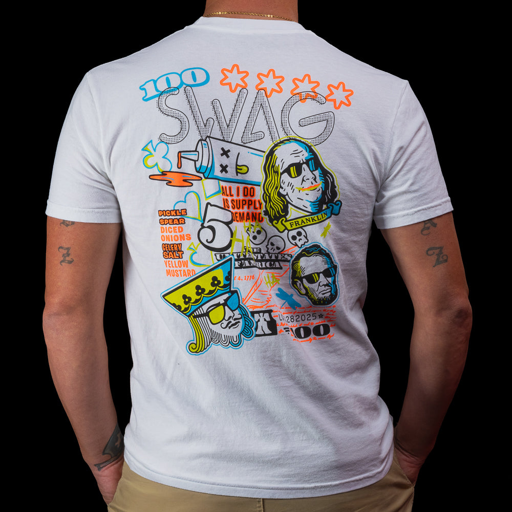 Back view of a white SWAG Golf T-shirt with a large multicolor “Greatest Hits” graphic featuring icons, text, and character art.