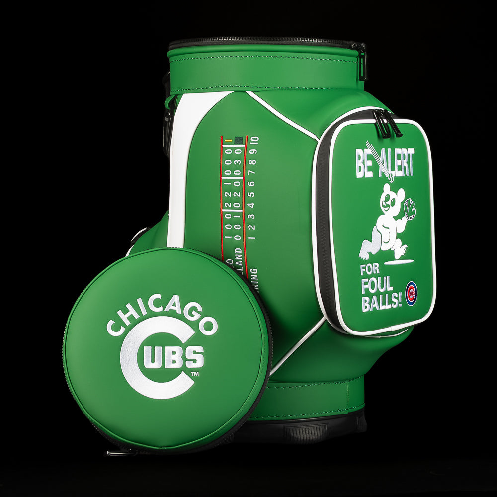 A green Chicago Cubs golf bag cooler with a matching round pouch in front, featuring white graphics, a scorecard print, and a front pocket with a cartoon bear and the text 'BE ALERT FOR FOUL BALLS!'.