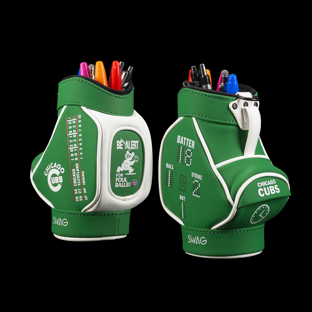 Two Chicago Cubs mini golf bag themed desk caddies shown side by side on a black background, each filled with pens and golf balls. The bags are green and white with Cubs-themed graphics, including 'Chicago Cubs', 'Be Alert', and team logos.