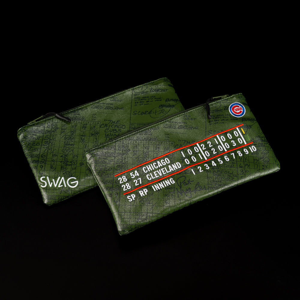 Two green zippered pouches with a textured card-like print, shown on a black background. One pouch has white 'SWAG' lettering, and the other features Chicago Cubs baseball card graphics with team colors and white text.