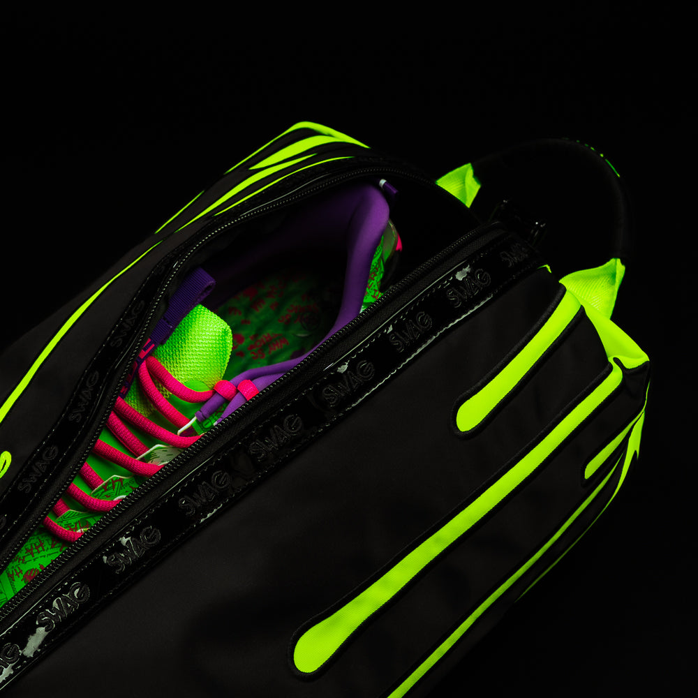 Close view of SWAG Neon Drip shoe bag with zipper opening revealing golf shoes and bright neon interior accents.