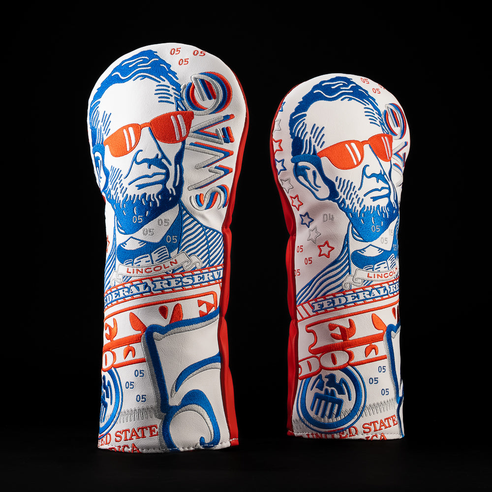 Front view of the RWB Gigantic Lincoln Driver Cover featuring an oversized Abraham Lincoln portrait wearing red sunglasses. Patriotic red and blue embroidery, currency-inspired artwork, stars, Federal Reserve design elements, and bold Americana details.