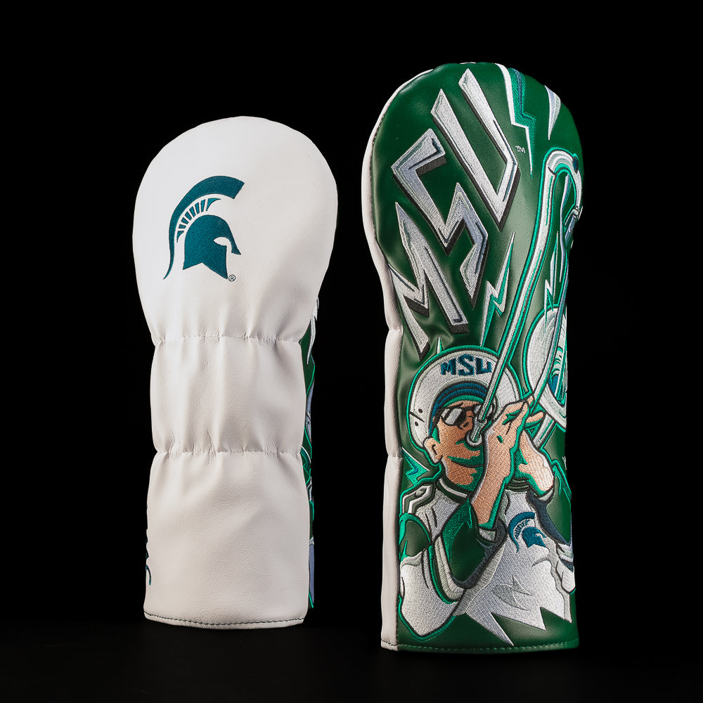 White and green Michigan State driver golf headcover featuring the Spartan helmet logo and an illustrated Spartans band player holding an oversized trombone.