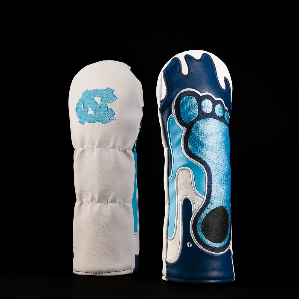White and navy UNC fairway golf headcover featuring the Carolina blue interlocking NC logo and an oversized Tar Heel footprint graphic with dripping details.
