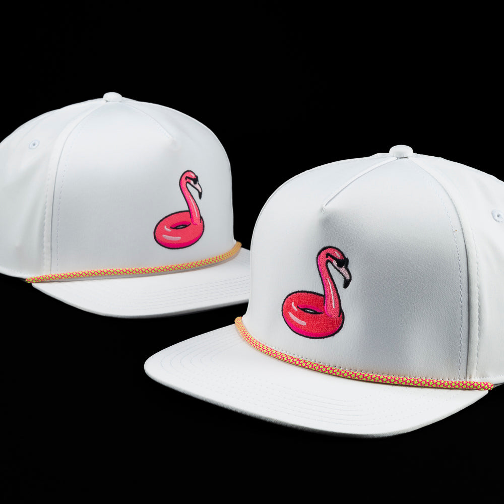 White snapback hat with embroidered pink flamingo floatie and coral rope detail across the brim, by SWAG Golf.