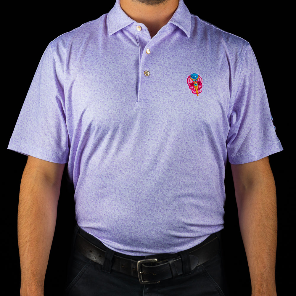 Ms. Pool Party Peter Millar performance polo with pink skull design and poolside embroidery on subtle lavender pattern background.