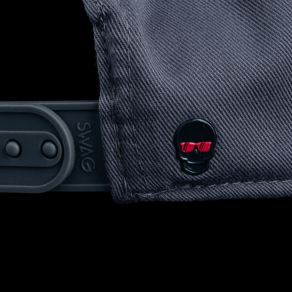 Side detail of SWAG Golf Blackout Bills Jefferson hat showing adjustable snapback strap and small skull pin with red sunglasses.