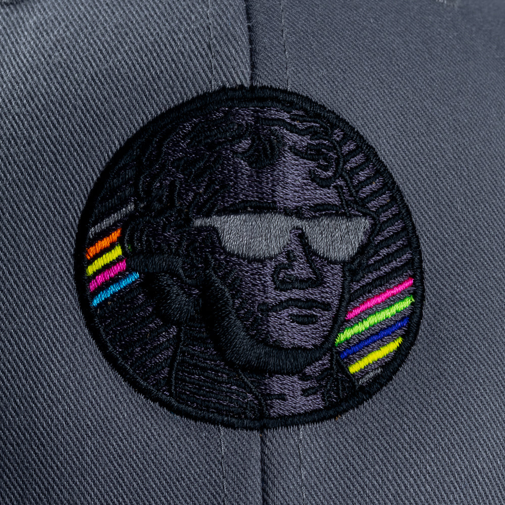 Close-up of embroidered Jefferson portrait patch on gray Blackout Bills hat with black thread and neon rainbow stripe accents.