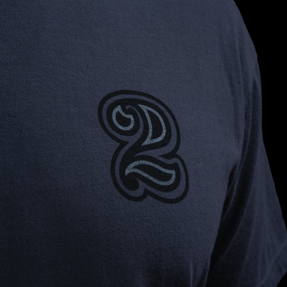 Close-up of tonal black script 2 chest logo on navy SWAG Golf Blackout Bills Jefferson t-shirt.