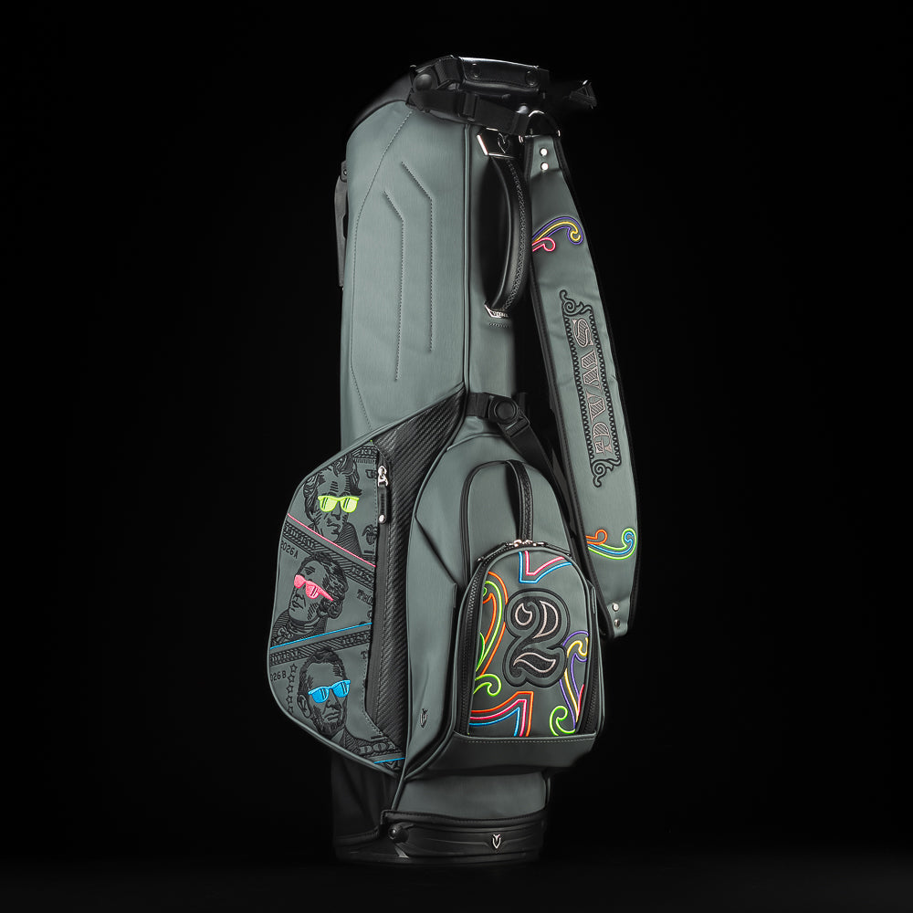 Gray SWAG Golf x Vessel golf stand bag with colorful dollar bill themed designs on a black background.