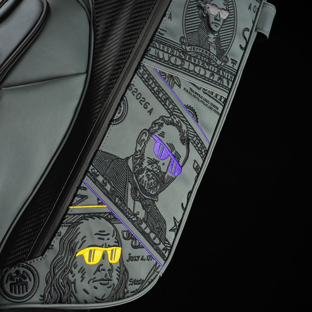 Gray SWAG Golf x Vessel golf stand bag with colorful dollar bill themed designs on a black background.