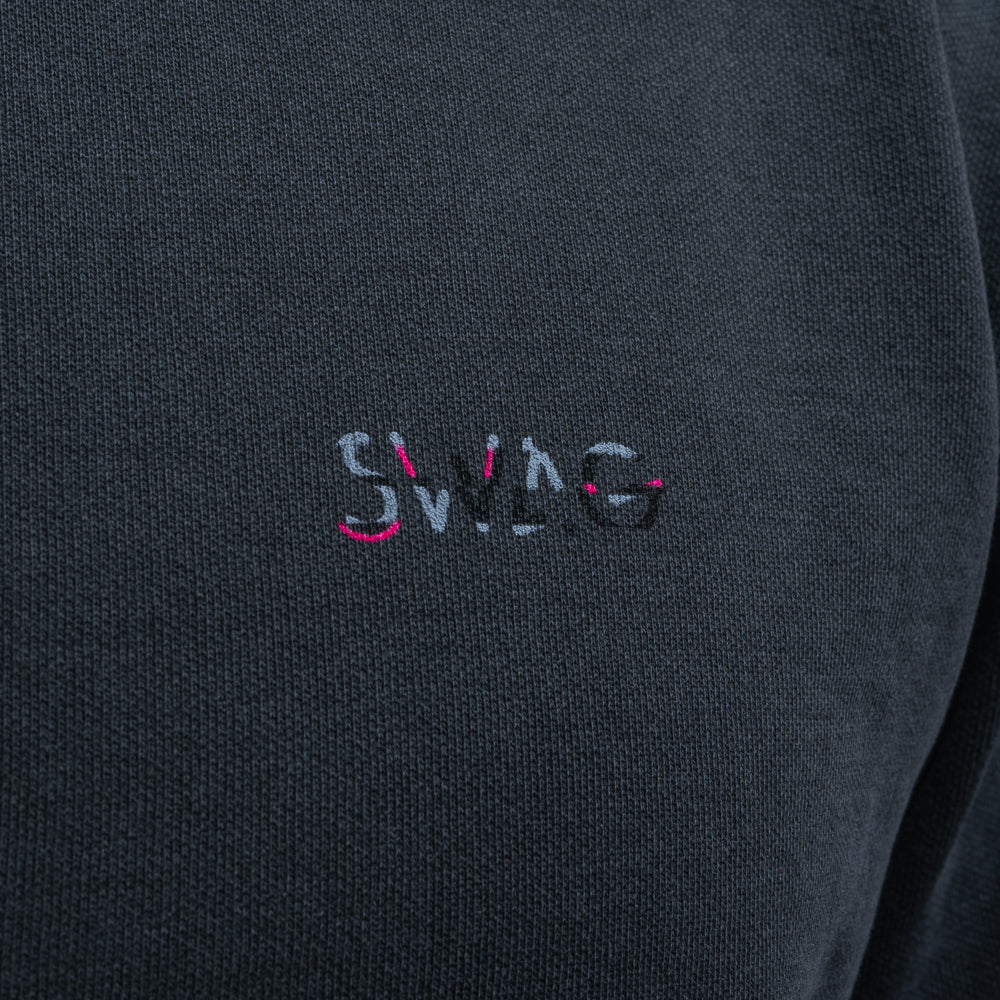 Close-up of embroidered SWAG logo on black Glitched Out Benji crewneck in pink and gray detail with glitch styling.