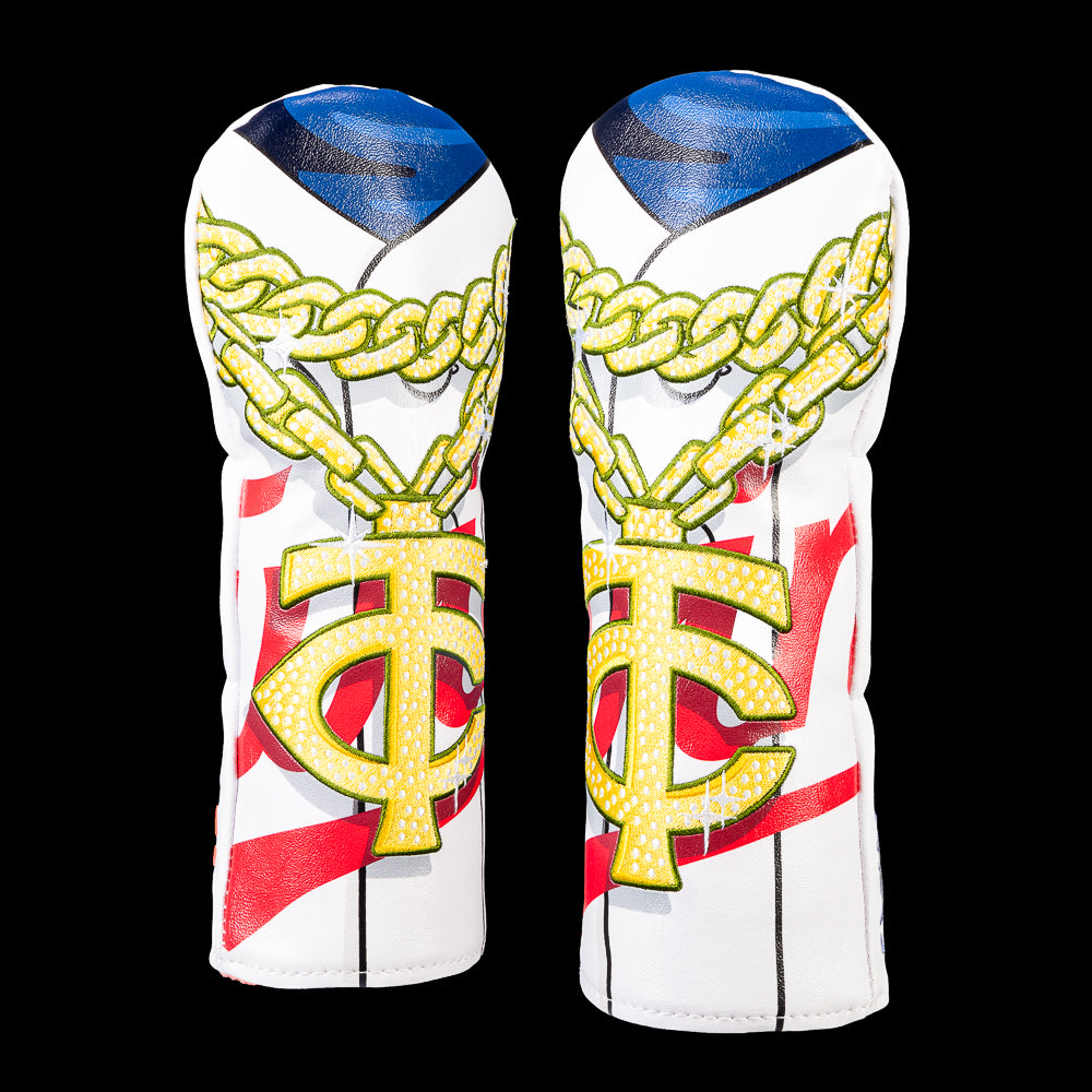 SWAG Golf Minnesota Twins fairway cover featuring an oversized diamond-studded TC pendant hanging from a gold link chain over a pinstriped jersey with bold red script accents and sparkling embroidered details.