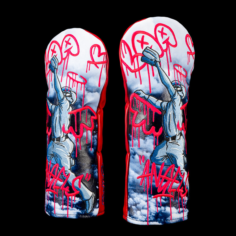 Officially licensed SWAG Golf Los Angeles Angels fairway cover featuring a baseball player creating dripping red Angels graffiti over a cloud-filled sky with embroidered detailing.