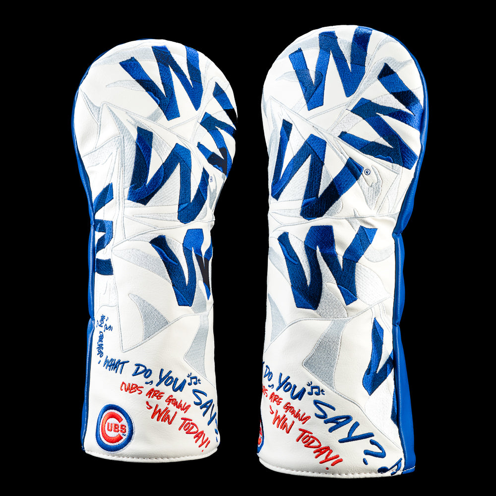 A pair of white golf club headcovers with blue and gray graphic patterns, featuring Chicago Cubs branding and a blue and red signature marker on a solid black background.