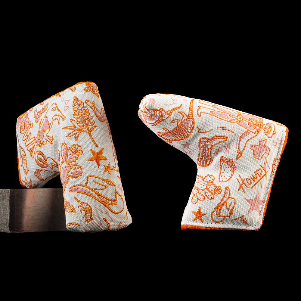 Angled front and back views of the SWAG Golf Locals Only Texas blade putter cover featuring orange embroidered Texas-inspired artwork including cowboy boots, a cowboy hat, longhorns, cacti, tacos, armadillos, stars, and Texas graphics on a white background.