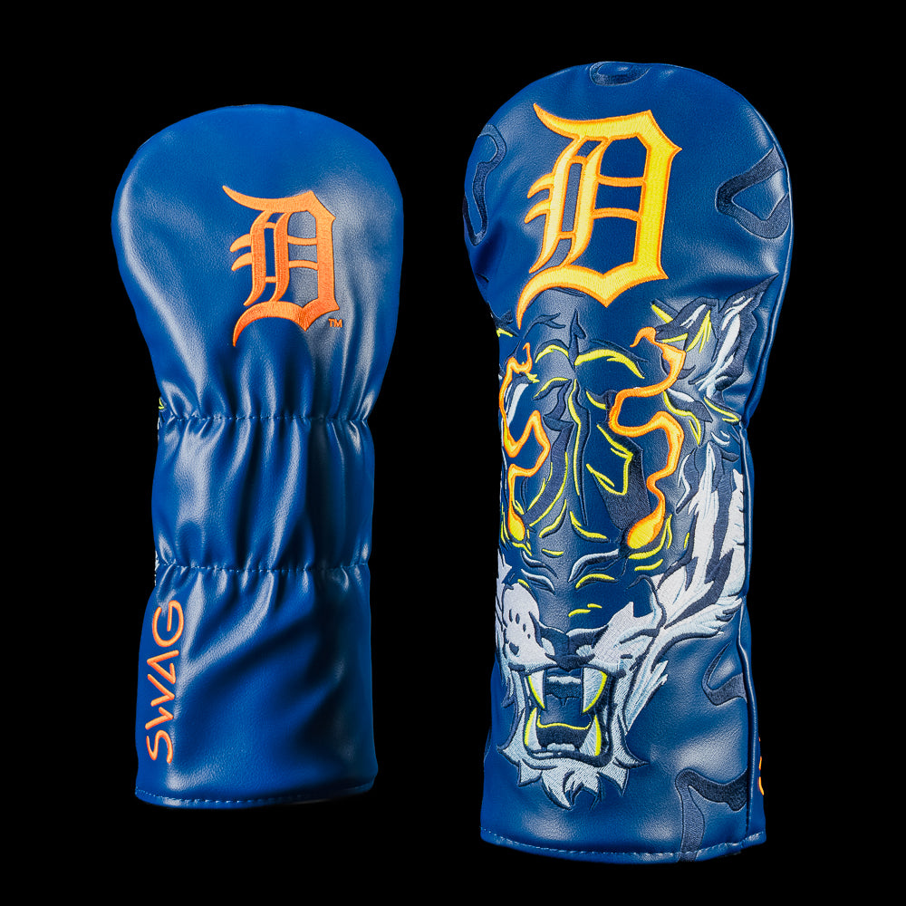 Detroit Tigers Night Prowl Driver Cover shown from the front and back. One side features a deep navy blue design with an embroidered "D" logo, the opposite side showcases a fierce white tiger with glowing orange accents. Orange SWAG branding along the side of the cover.