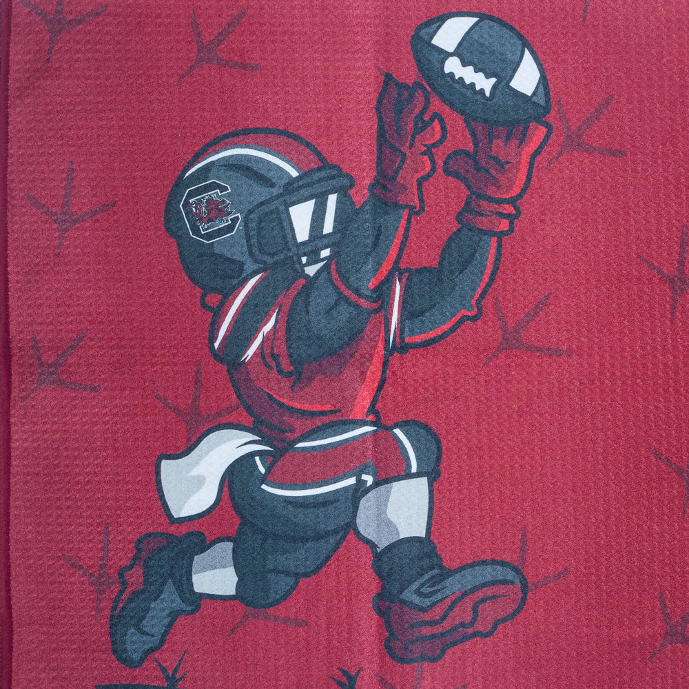 Red golf towel with University of South Carolina Gamecocks football player graphic and logo on a black background