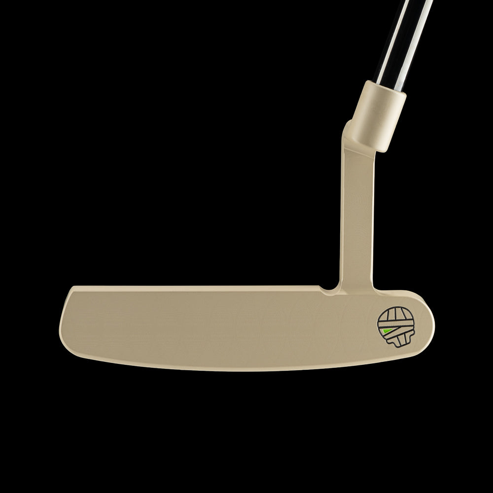 A beige golf putter shown from the side against a solid black background, featuring a small green and black logo near the base of the shaft.
