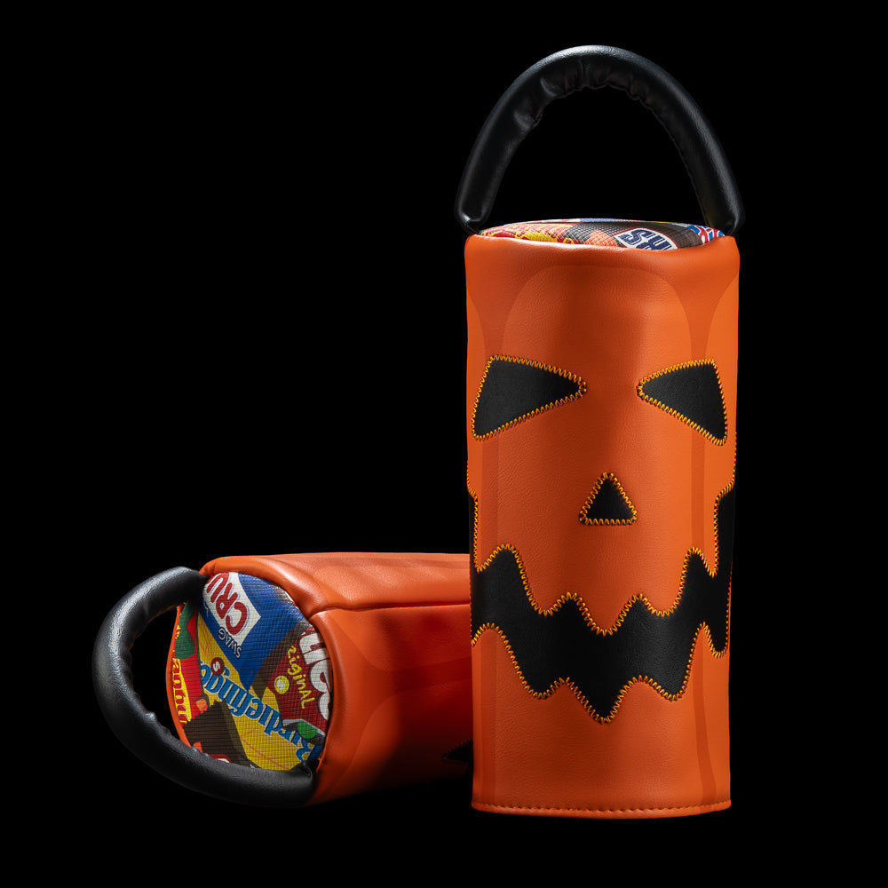 An orange Halloween-themed cylindrical driver headcover with a black handle, featuring a stitched jack-o'-lantern face on the front. A second view shows the open interior lined with colorful candy illustrations.
