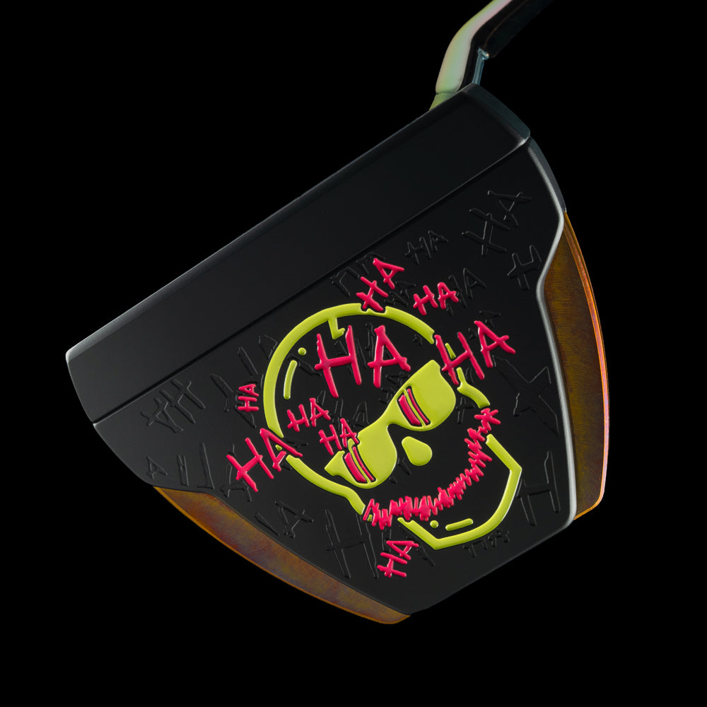 A black golf putter head featuring a bright yellow and red skull graphic with 'HA HA HA' text, shown against a solid black background.