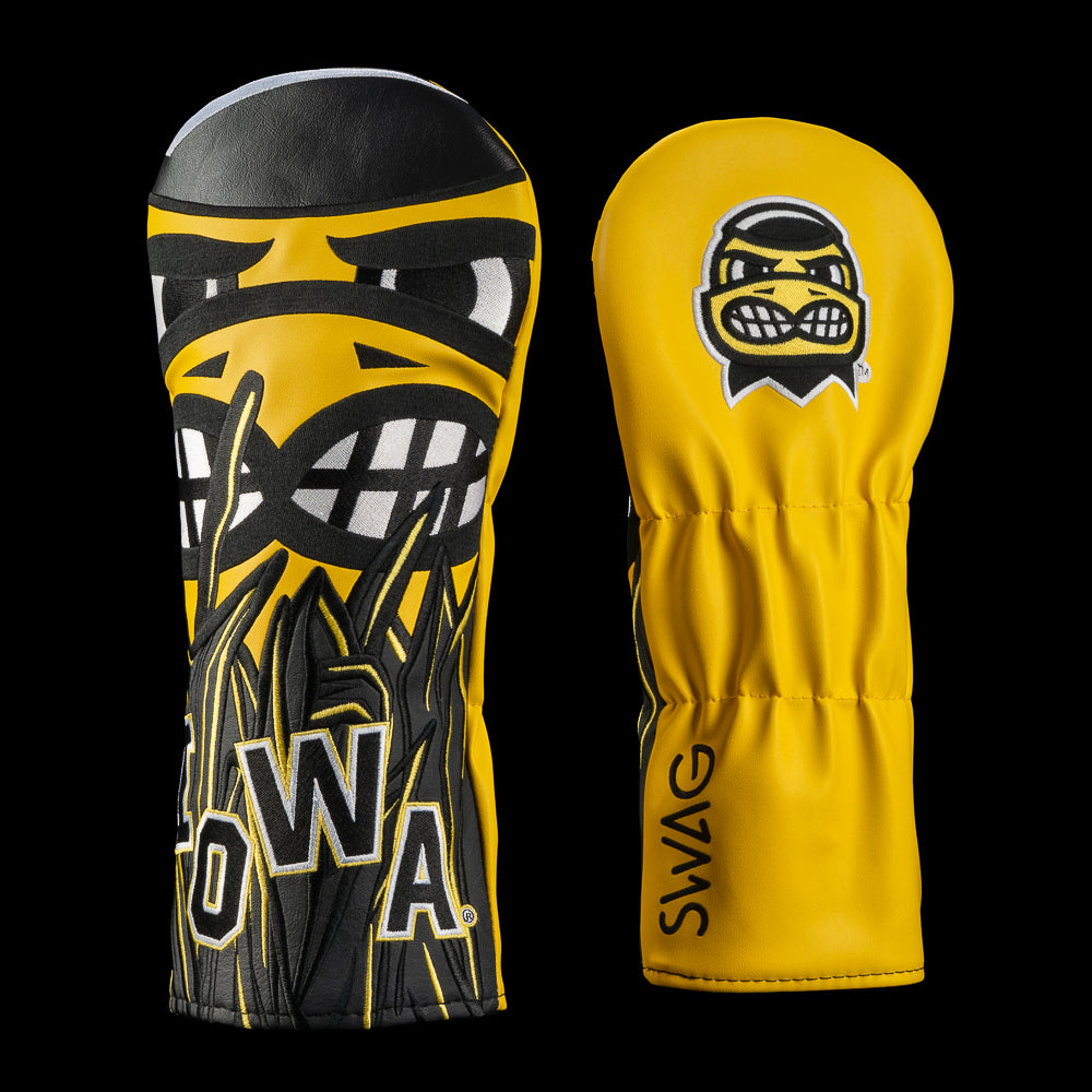 Two yellow and black golf club headcovers on a black background, one showing a large stylized face graphic with 'IOWA' lettering and the other showing a smaller matching logo with the word 'SWAG' on the sleeve.