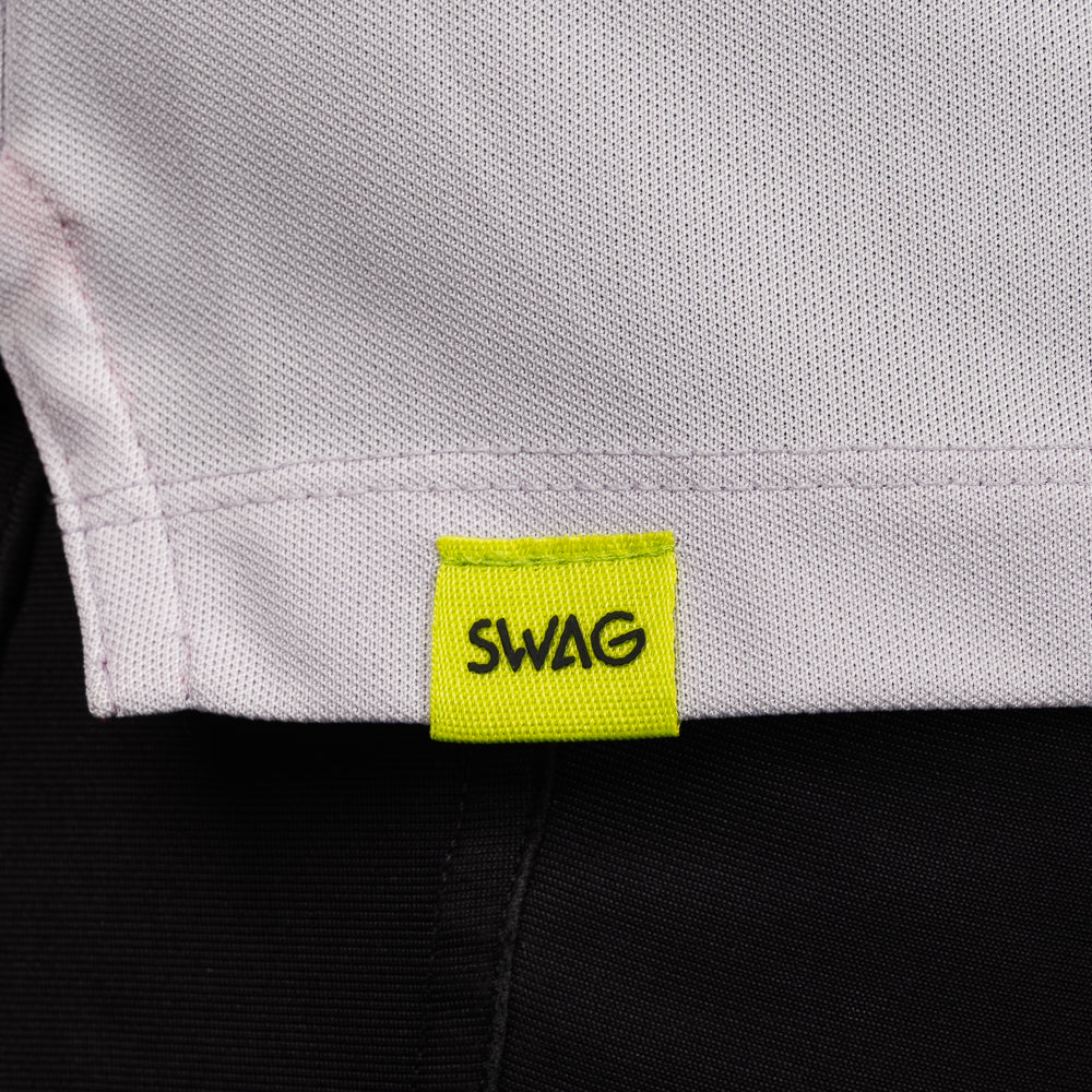 SWAG Golf Lavender Script Tech Polo hem detail featuring the signature neon SWAG woven tag.