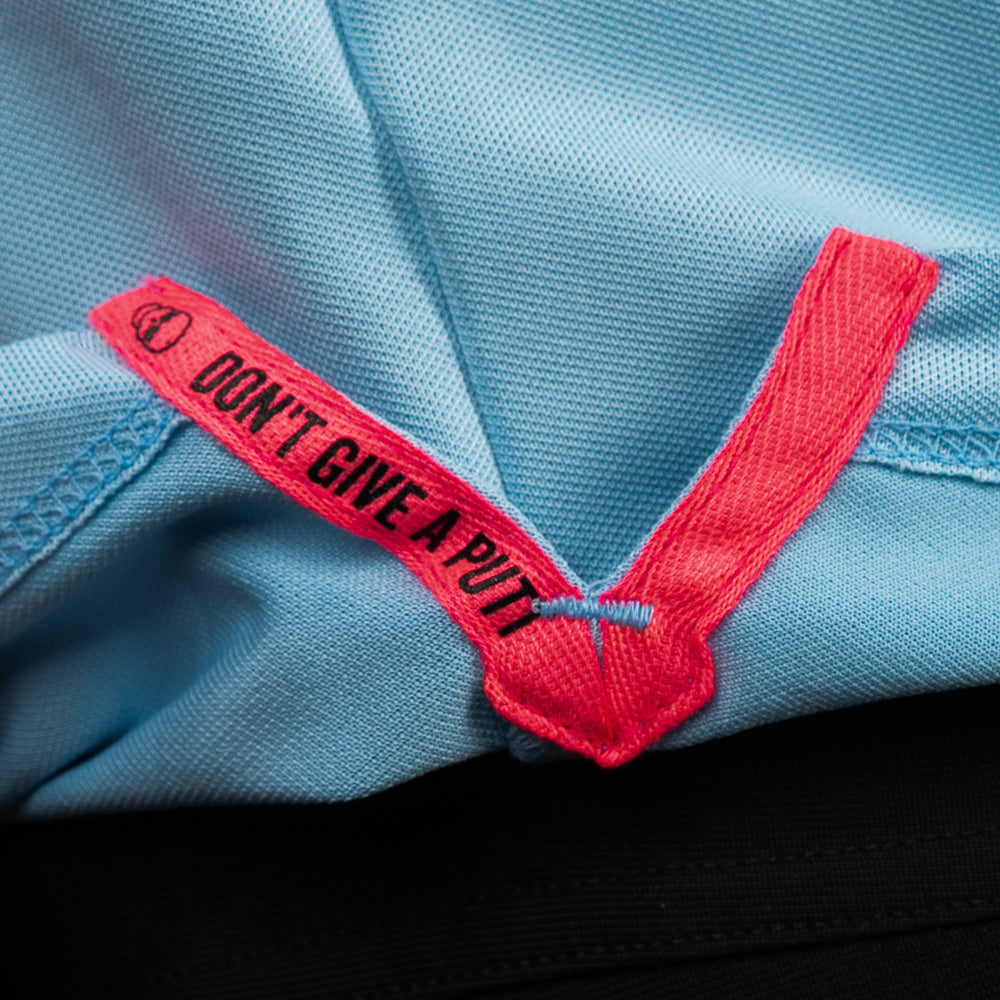 Interior detail of SWAG Golf Sky Blue Script Tech Polo featuring signature Don't Give A Putt neck embroidery in vibrant pink contrast.