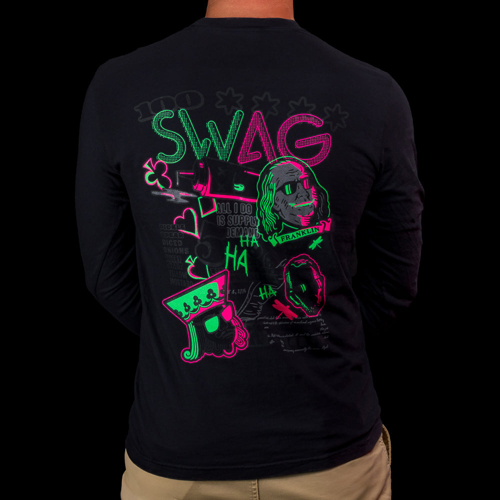 Back view of a black SWAG Golf long-sleeve shirt featuring a neon green and pink “Greatest Hits” graphic with icons, text, and character art.
