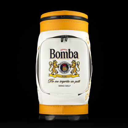 Front pocket close-up of the Bomba Den Caddy golf bag showing embroidered Bomba cerveza crest and slogan detail.