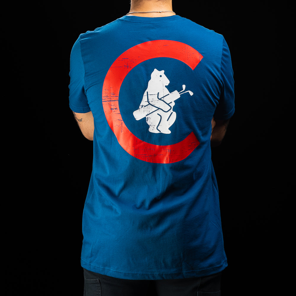 A person viewed from the back wearing a blue short-sleeve T-shirt with a large red circular Chicago Cubs-style logo and a white bear graphic on the back, against a black background.