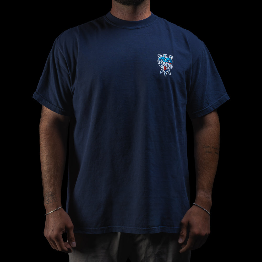 Person wearing a SWAG Golf navy blue short sleeve graphic t-shirt with a tattoo themed logo on the chest against a black background