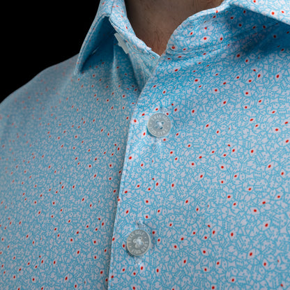 Close-up of a light blue polo shirt with a white and red dice pattern, worn by a model. The shirt features a classic collar and white-toned buttons with SWAG Golf engraving.