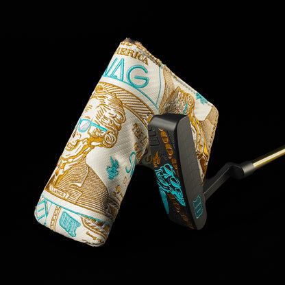 A golf putter with a black head and gold shaft, fitted with a fabric cover printed in a gold and turquoise design resembling a US dollar bill, shown against a solid black background.