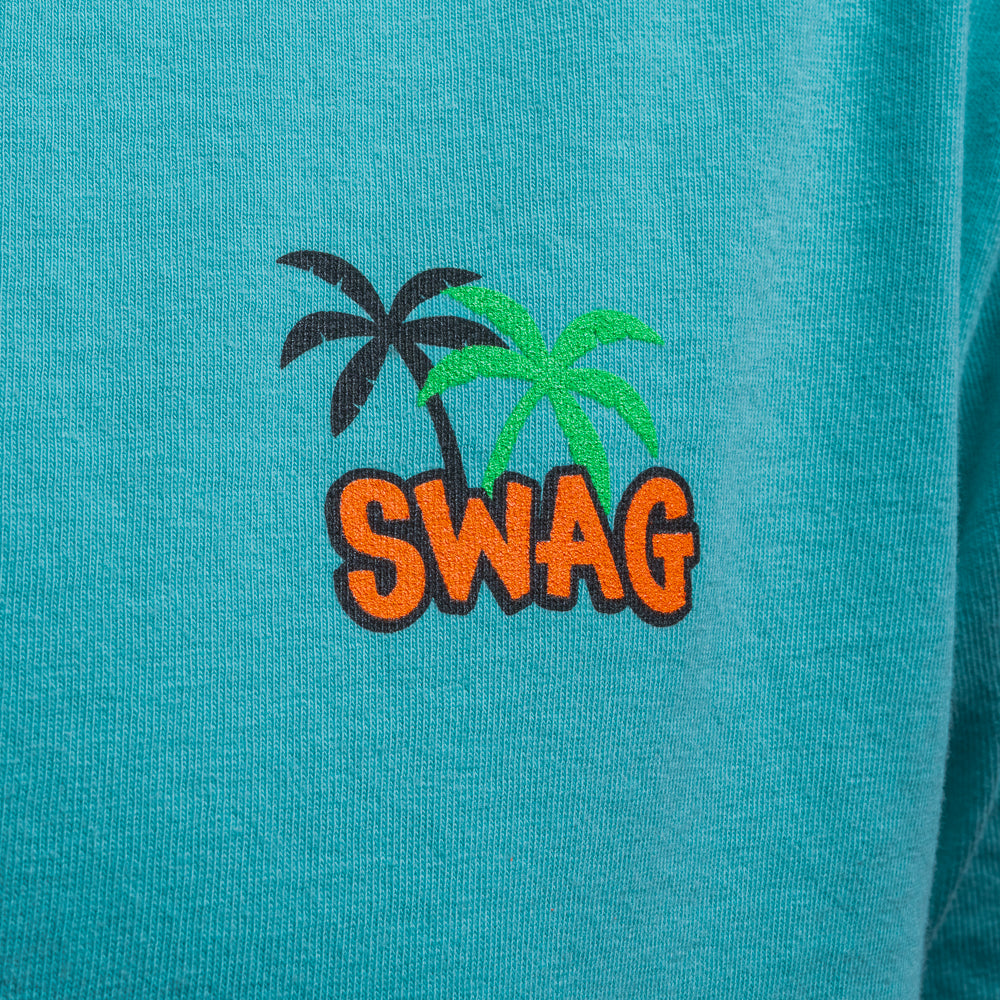 Close up of Pelican T-Shirt in aqua featuring SWAG logo with black and green palm trees on chest.