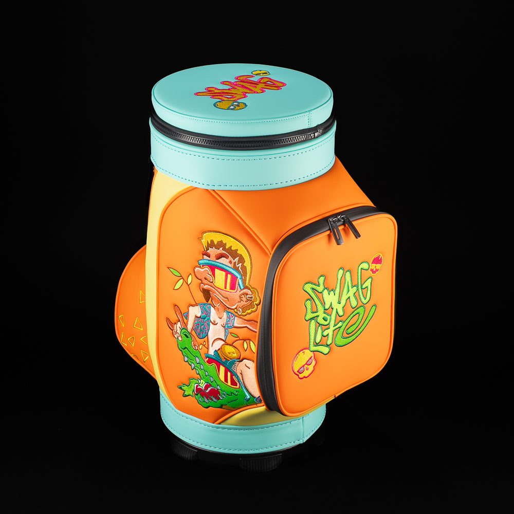 Close up of front pocket on SWAG Florida Man Den Caddie bag showing green SWAG embroidery and pink skull accent on bright orange panel.