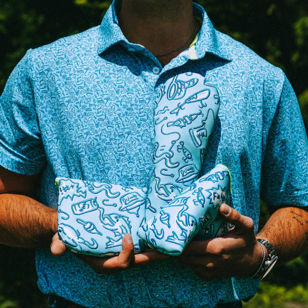 Person wearing a blue patterned polo shirt holding matching golf headcovers.
