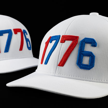 Side view of the 1776 hat showcasing raised embroidered 1776 lettering in patriotic red and blue on a white performance cap.