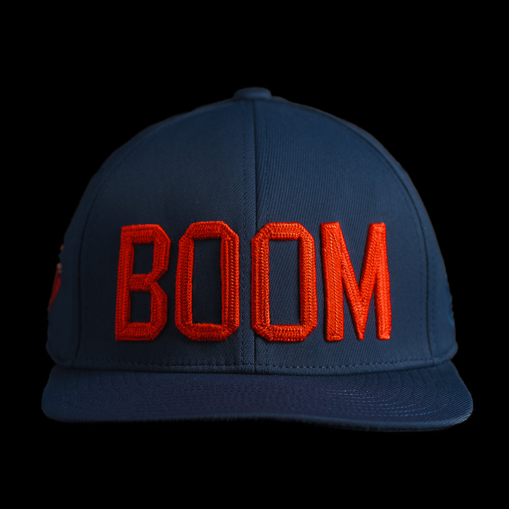 Front view of the BOOM hat featuring bold red embroidered BOOM lettering on the crown of a navy performance cap.