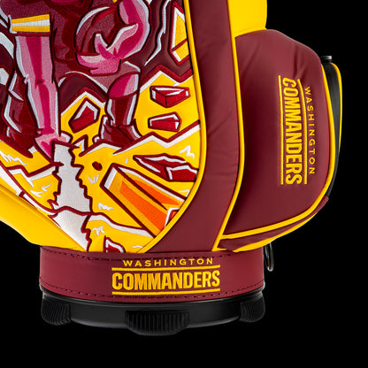Close-up of the embroidered Commanders logo on the front pocket with the Commander mascot artwork in the background.