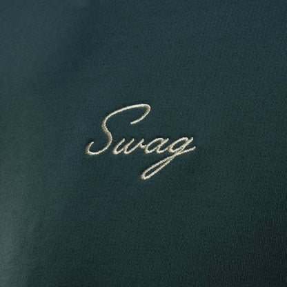 Person wearing a nordic green long sleeve performance golf hoodie with 'Swag' logo.