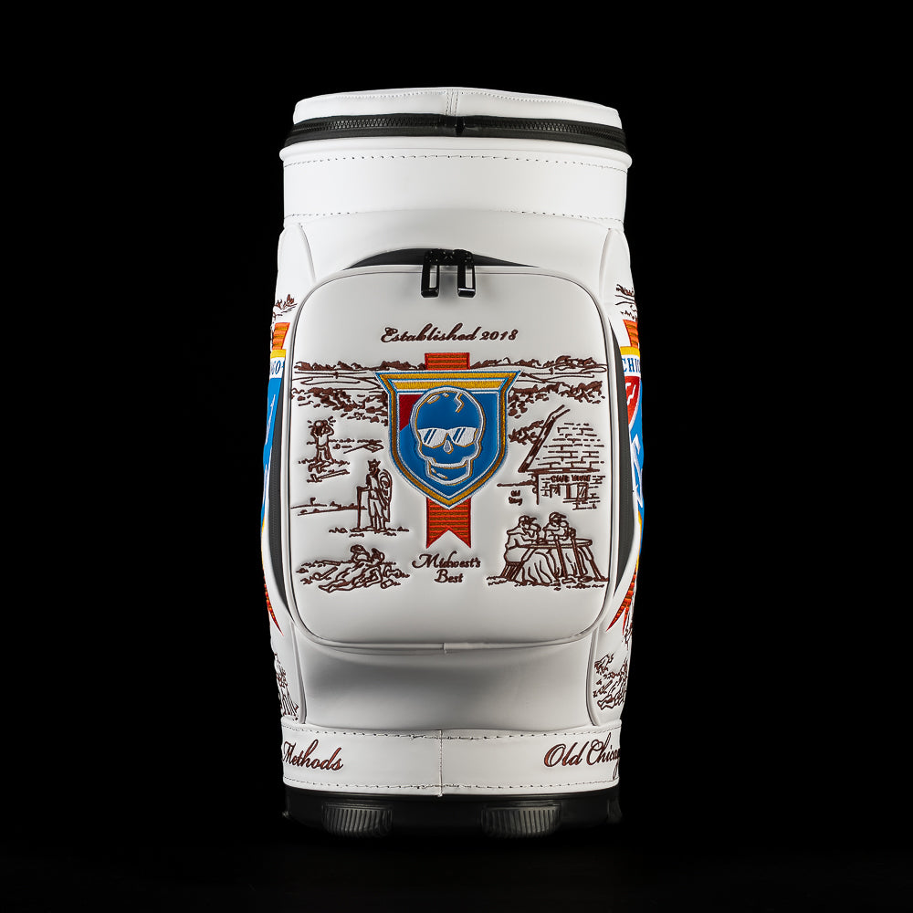 Back view of the Old SWAG Den Caddy Cooler featuring a zippered white pocket with a blue skull shield, brown Chicago illustrations, “Established 2018” and “Midwest’s Best” embroidery.