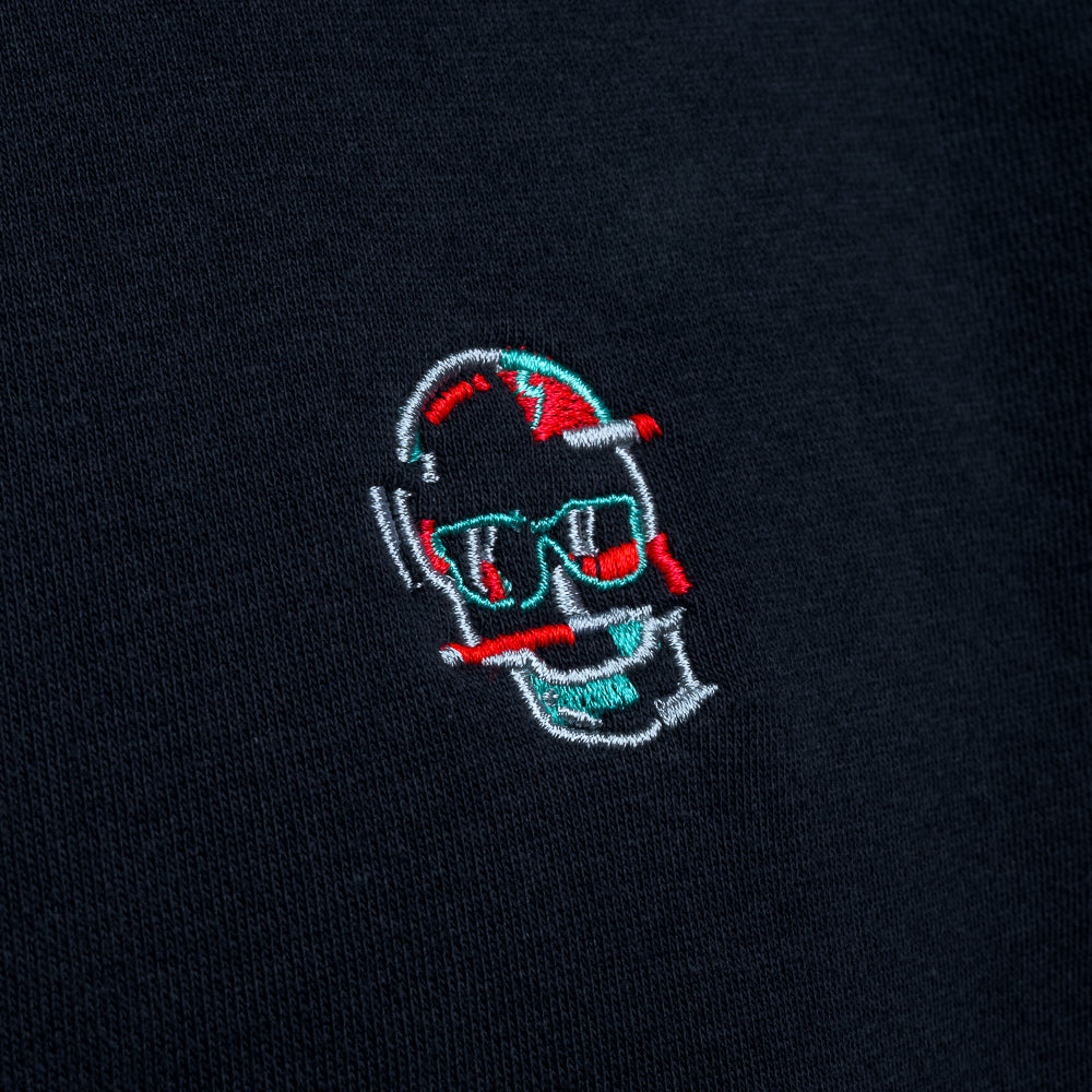 Close-up of embroidered glitch skull logo on black SWAG Golf hoodie in red, teal, and white thread detail.