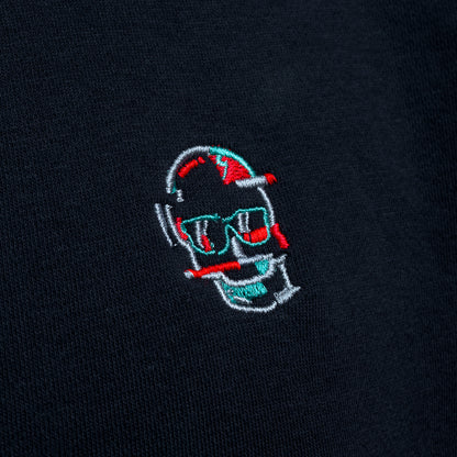 Close-up of embroidered glitch skull logo on black SWAG Golf hoodie in red, teal, and white thread detail.
