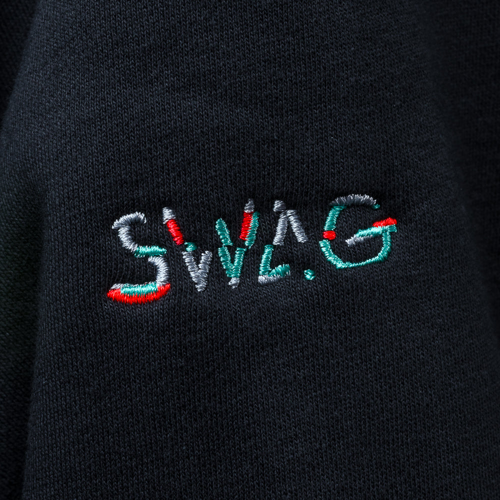 Close-up of embroidered SWAG logo on sleeve of black SWAG Golf Glitch Skull Hoodie in red, teal, and white stitching.