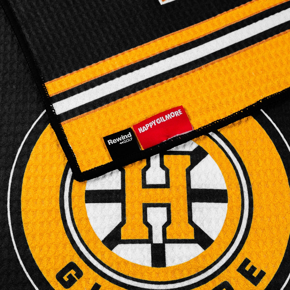Black performance golf towel with yellow stripes and a Happy Gilmore Hockey logo.