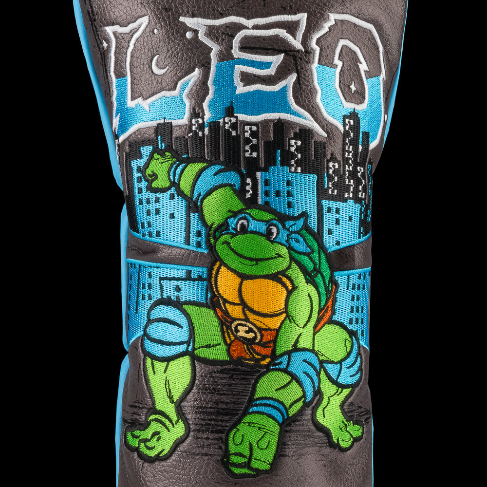 Blue TMNT Leo driver cover with swords and city backdrop.