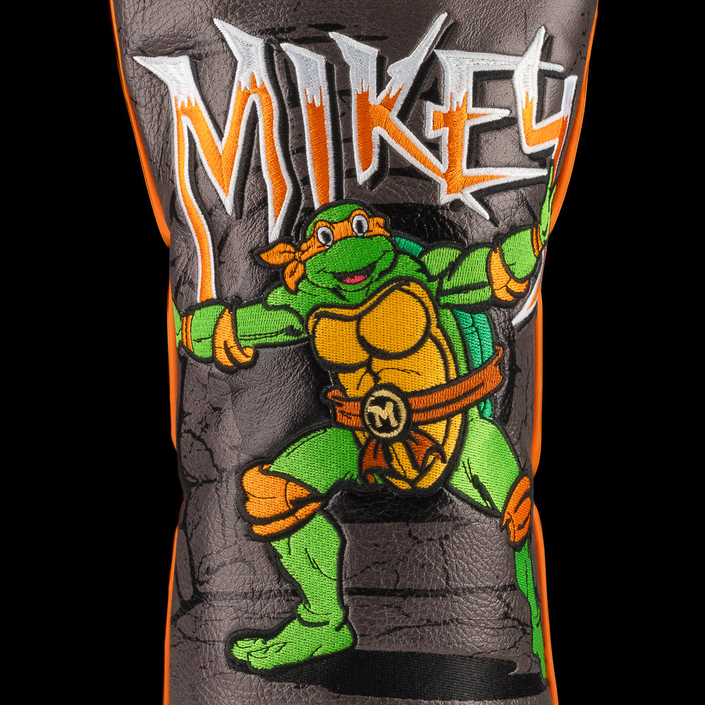 Orange TMNT Mikey driver cover with cartoon design.