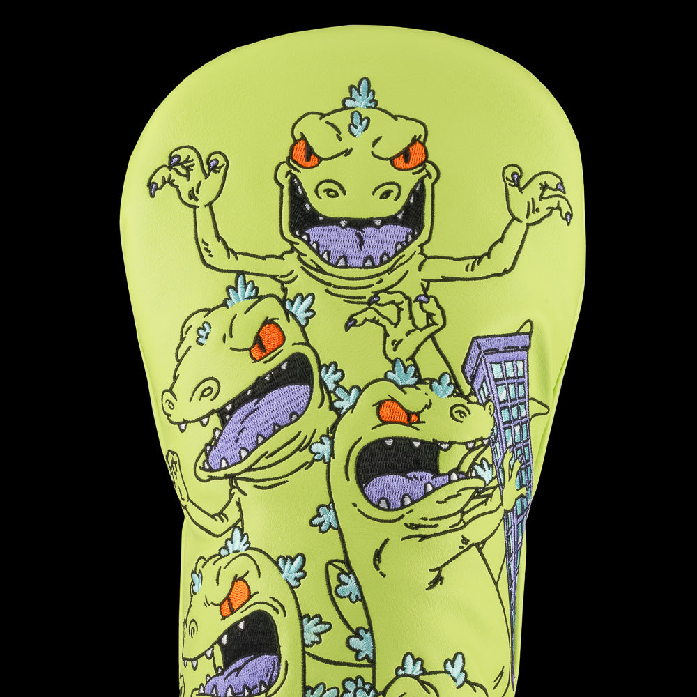 Green Rugrats Reptar driver cover with stacked cartoon Reptar design holding a building, bold Rewind Golf headcover style.